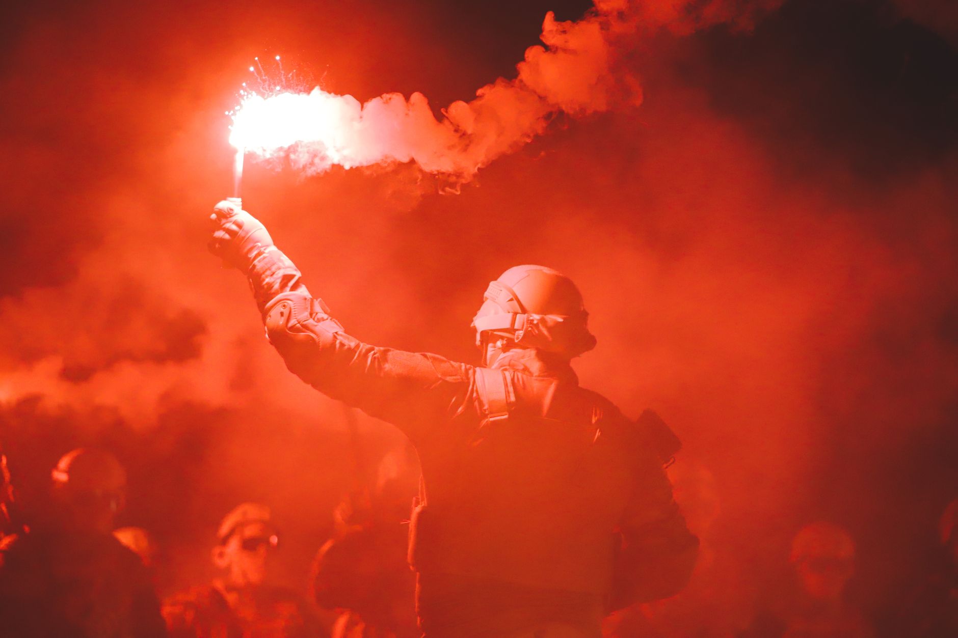 soldier holding flare in red smoke at night